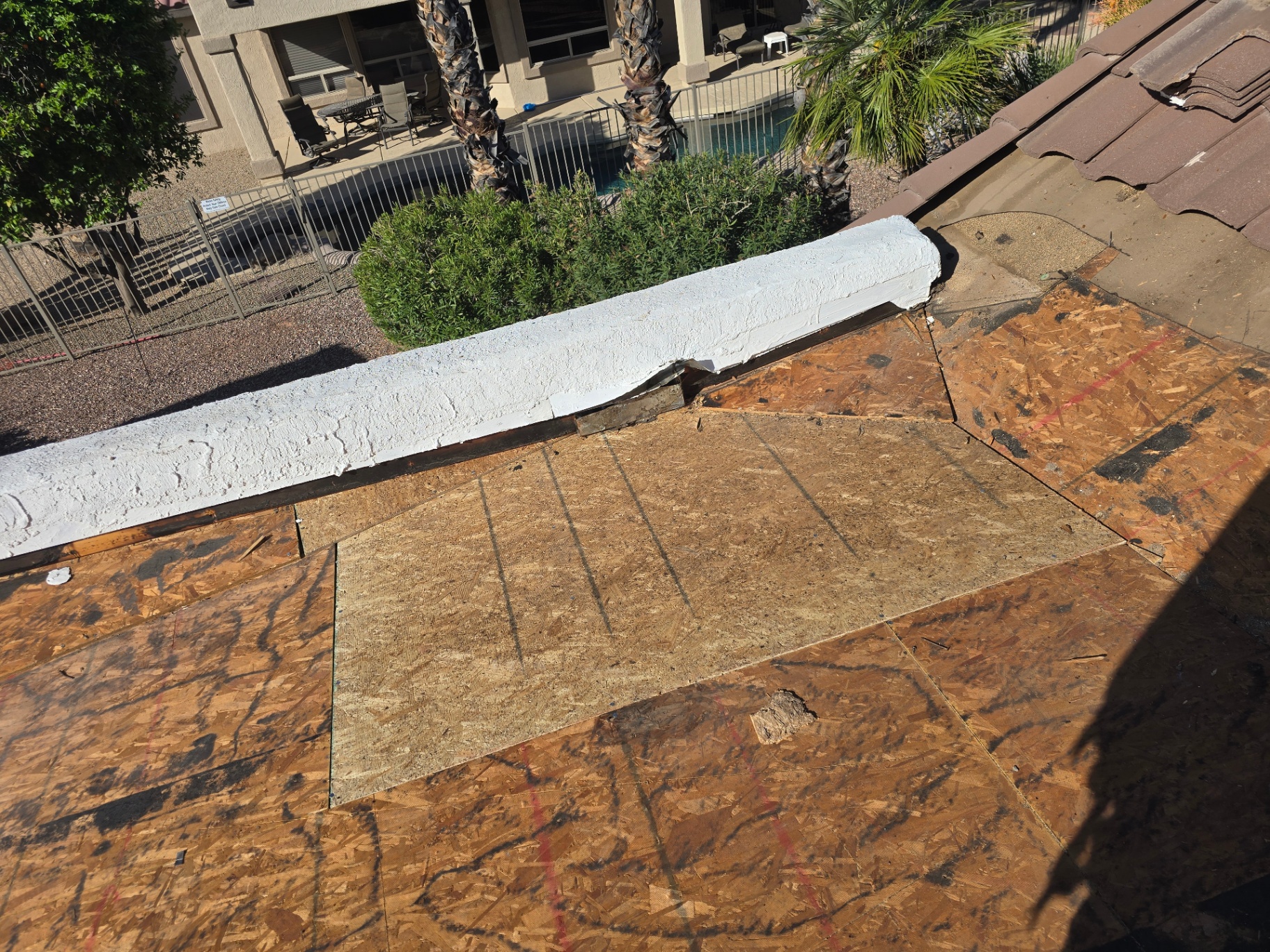New plywood decking installed alongside freshly coated parapet