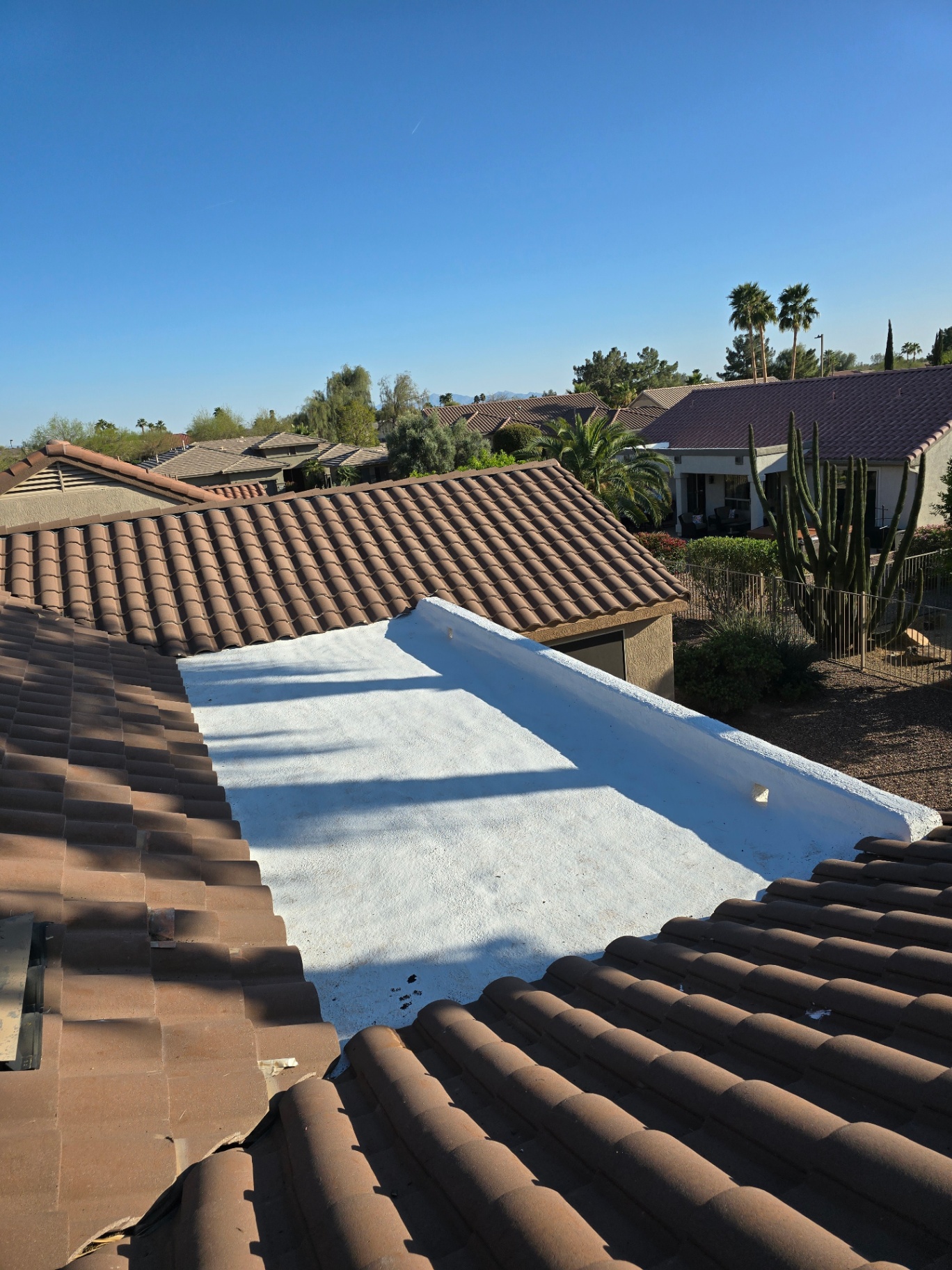 Reflective white coating on a flat roof section between tile roof slopes