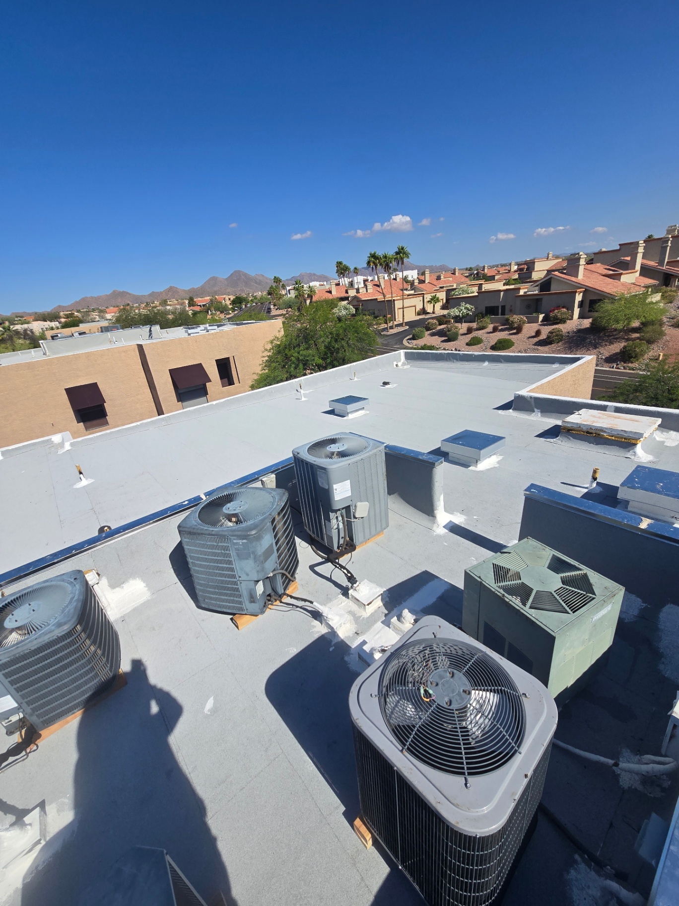 Rooftop view of finished flat roof system around HVAC units with bright white coating