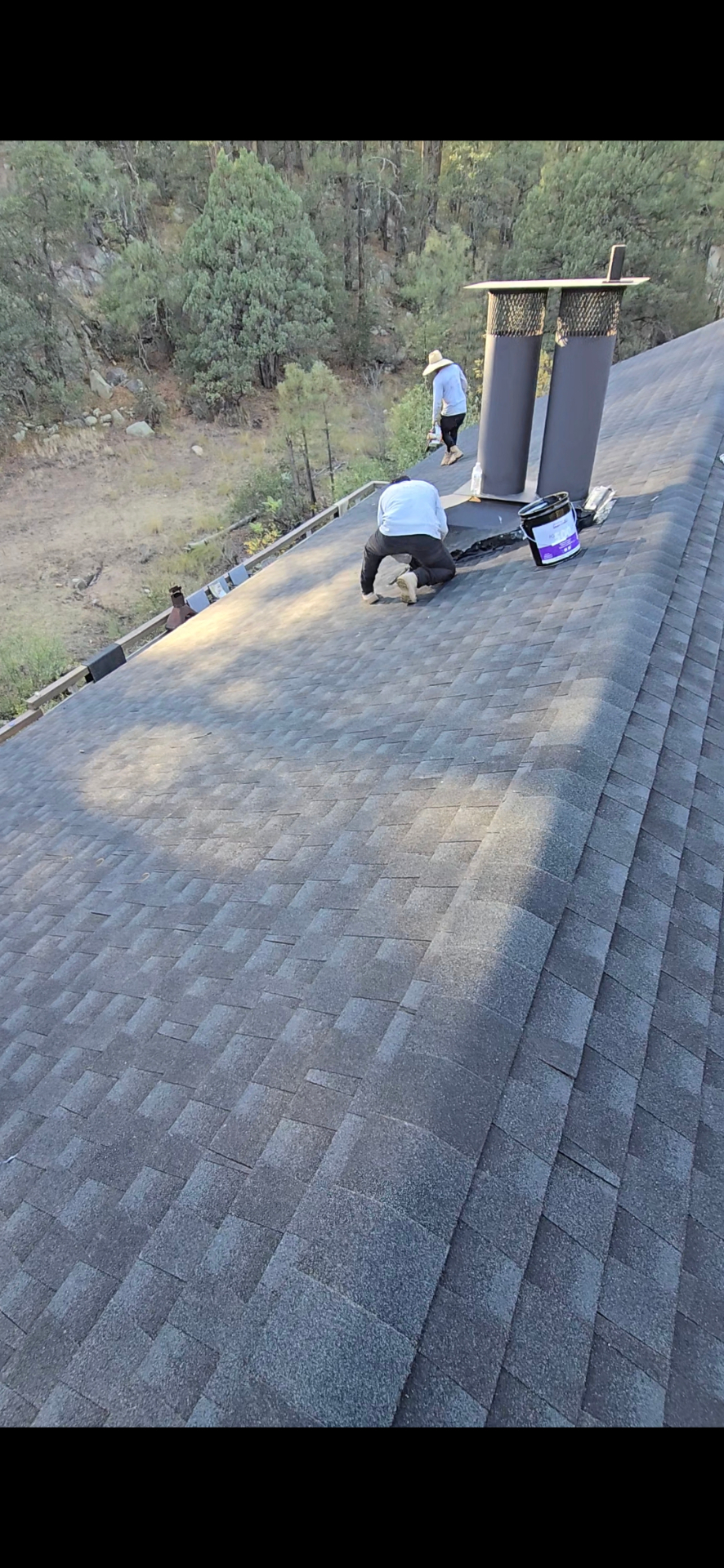 Roof Doc crew installing flashing around dual chimney flues on a mountain shingle roof