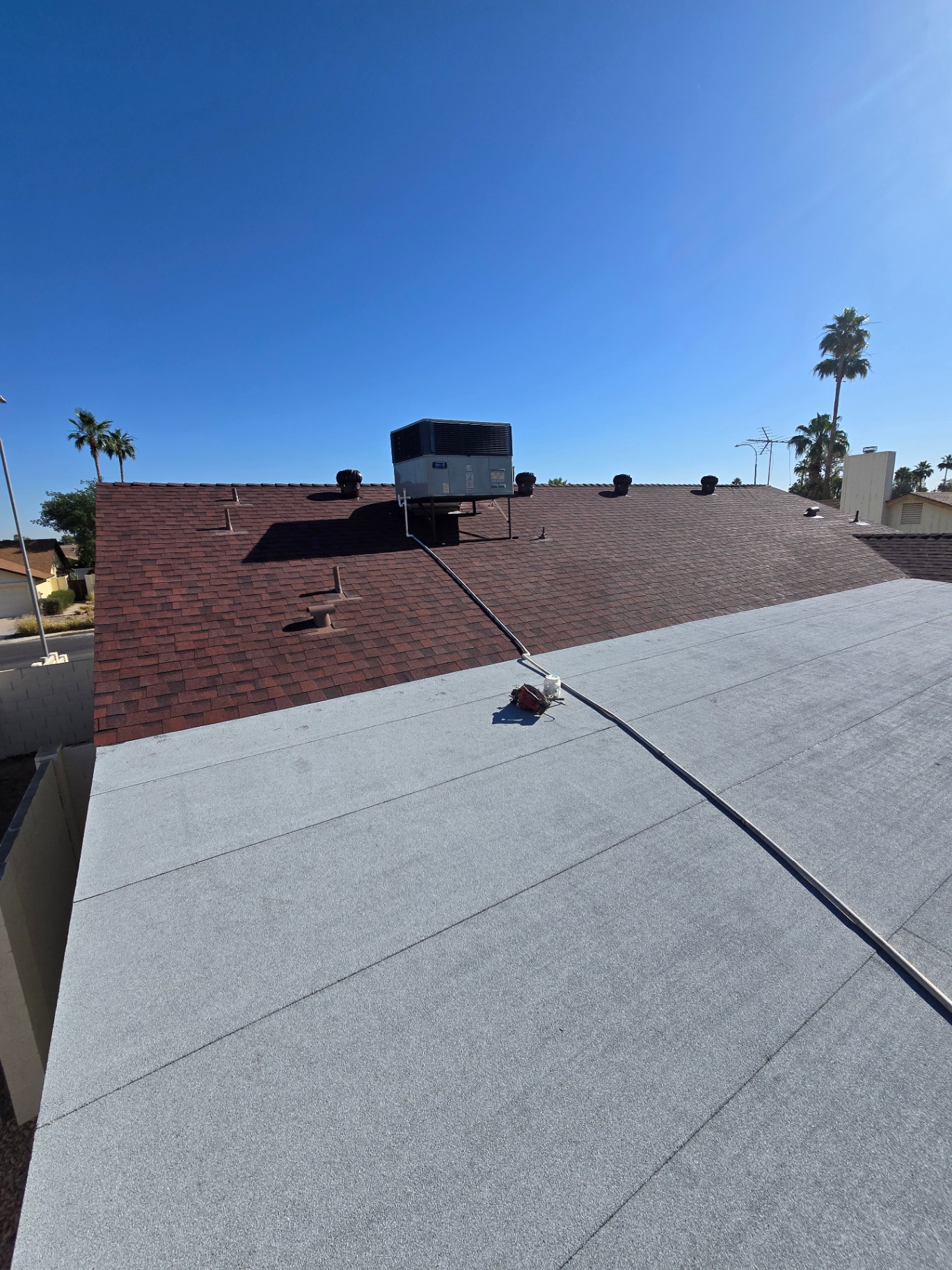 Combo roof — red architectural shingles paired with a modified bitumen flat section