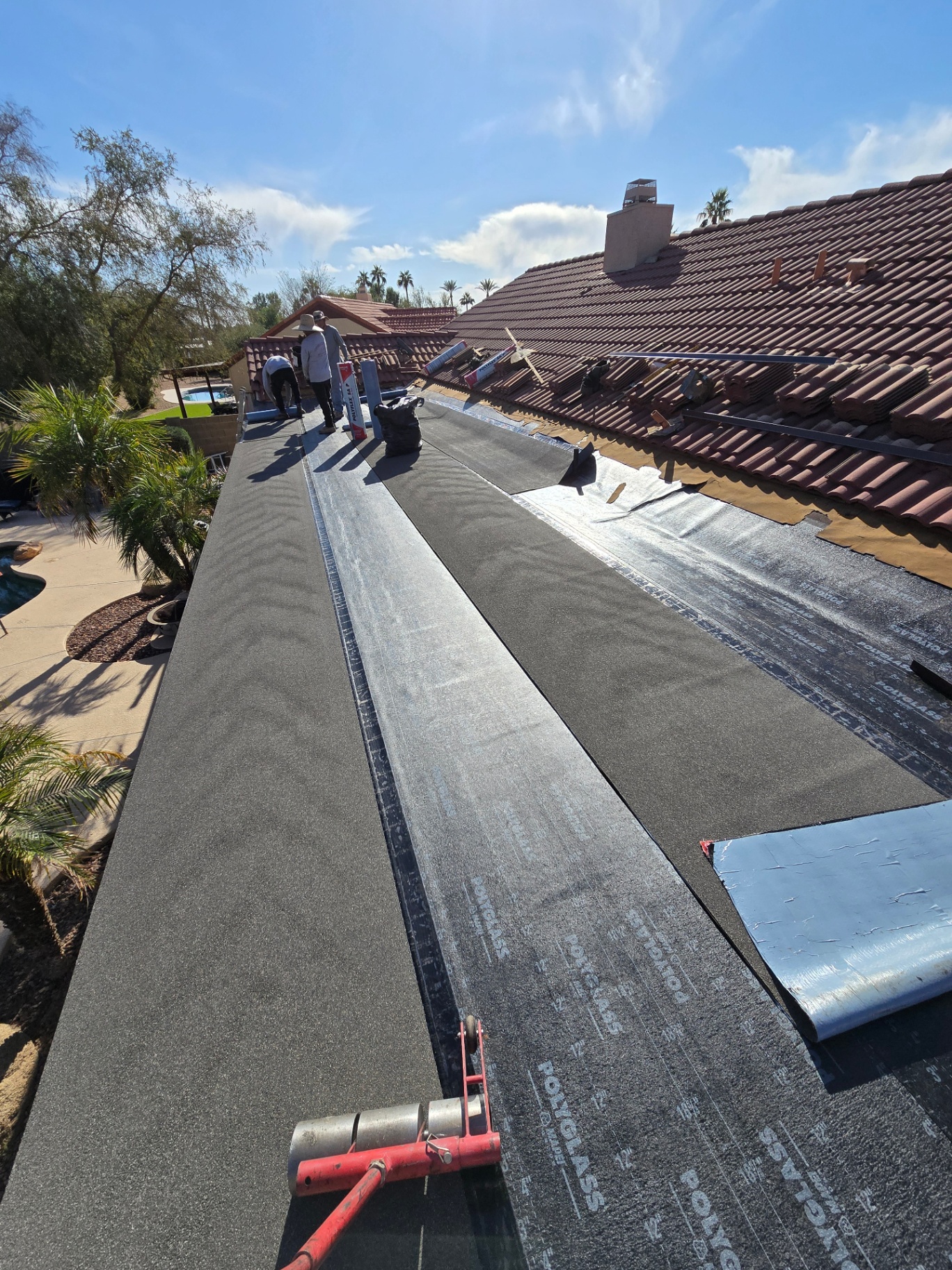 Patio roof tie-in with new modified bitumen membrane against existing tile roof