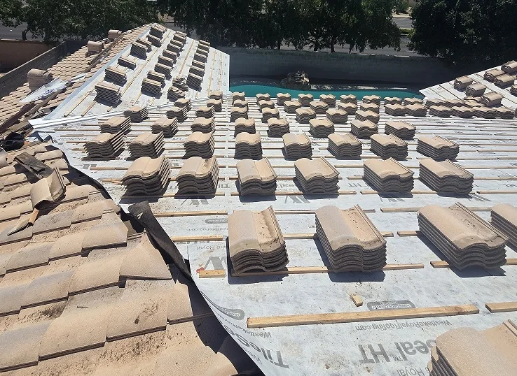 Roof Doc tile roof replacement in progress with stacked tiles and new underlayment
