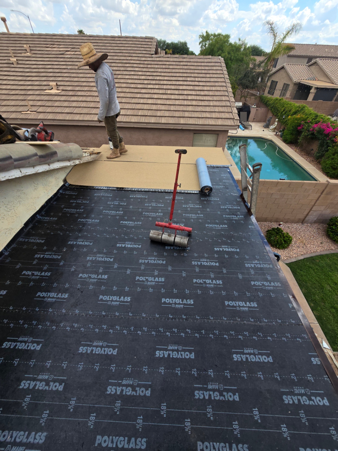 Patio roof transition from tile to flat membrane with cap sheet roller in place