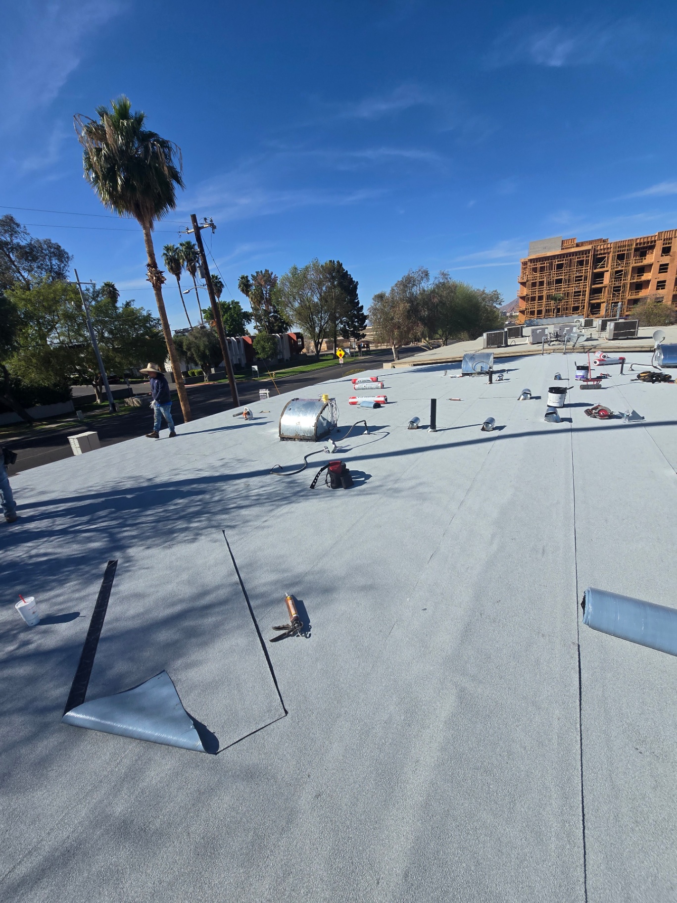 Granulated cap sheet flat roof under installation with torch-down equipment staged