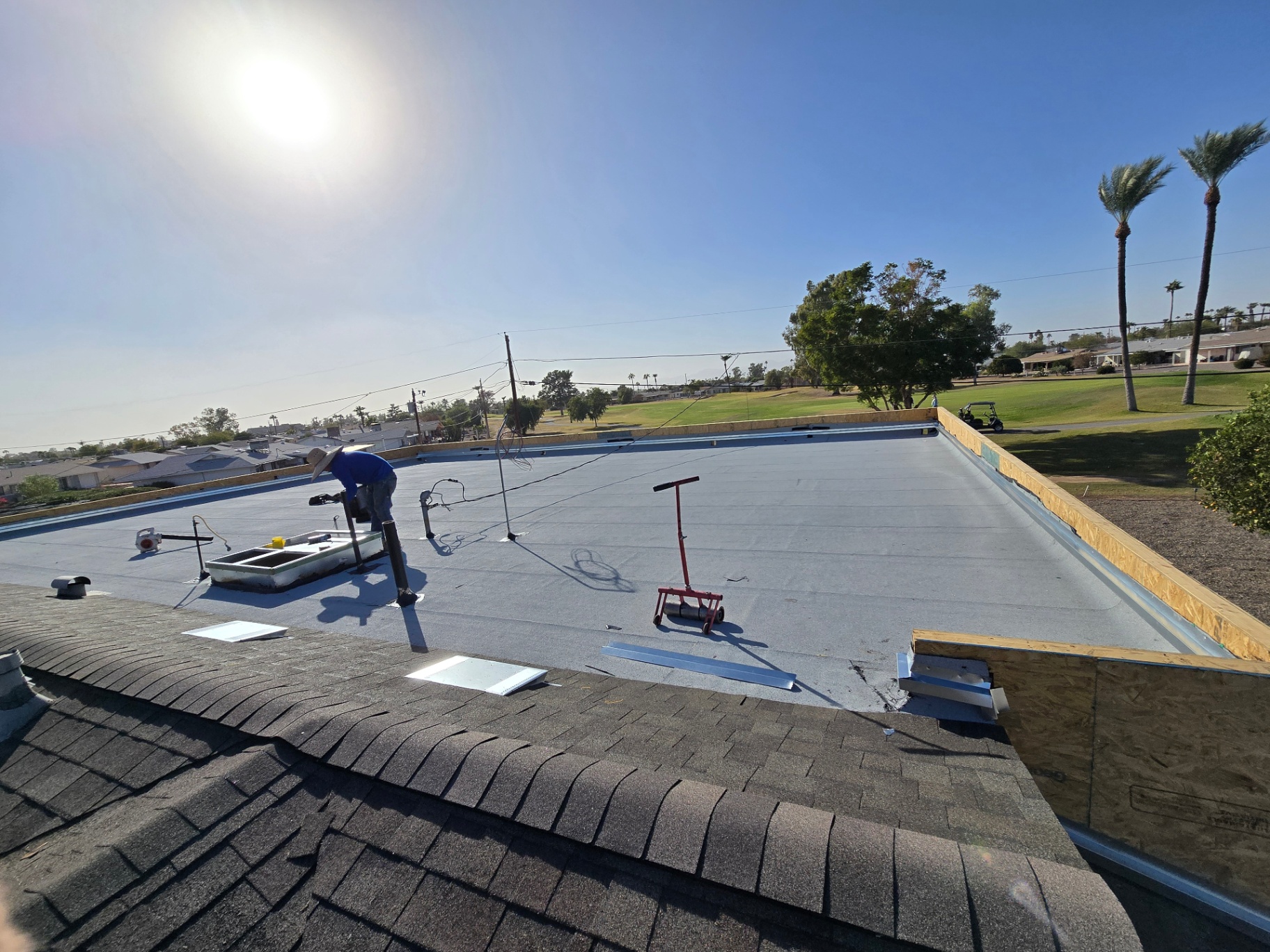 Freshly installed cap sheet on a flat roof with new drip edge and clean perimeter