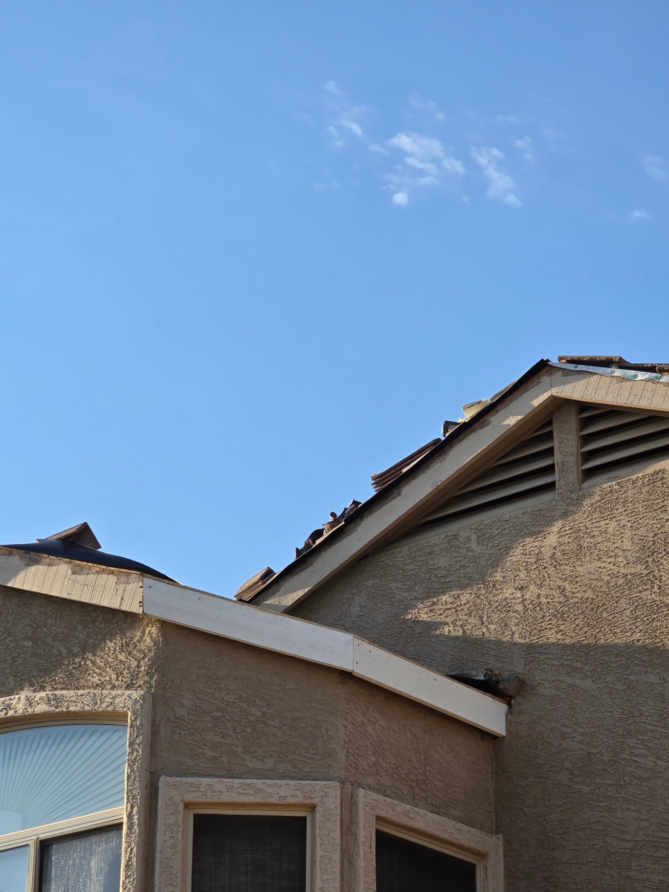 Tile and fascia repair in progress with new wood trim installed along the rake