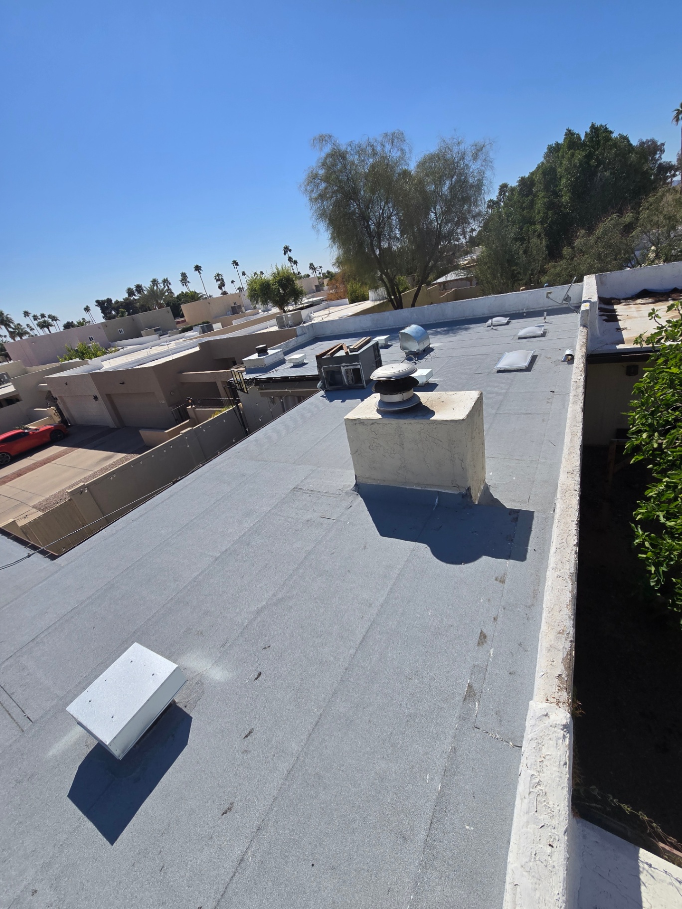 Completed flat roof with new vents, scuppers, and crisp parapet flashing