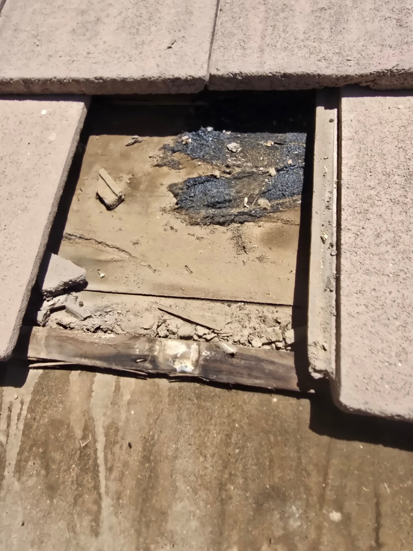 Pulled tile revealing torn underlayment and exposed felt over the deck