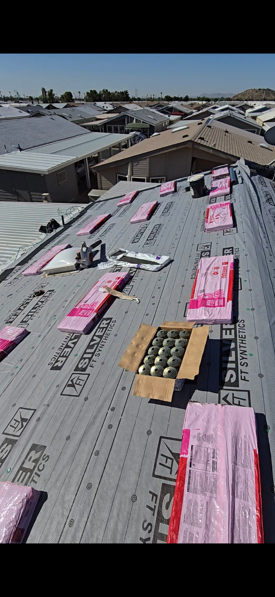 Shingle bundles and coil nails staged on synthetic underlayment, ready to load out