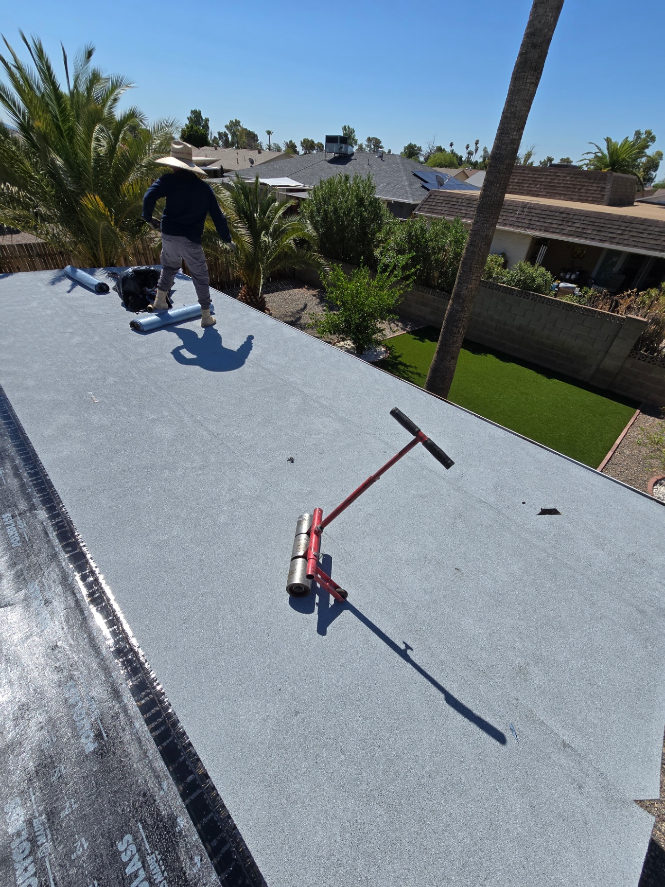 Crew member finishing patio roof with reflective granulated cap sheet