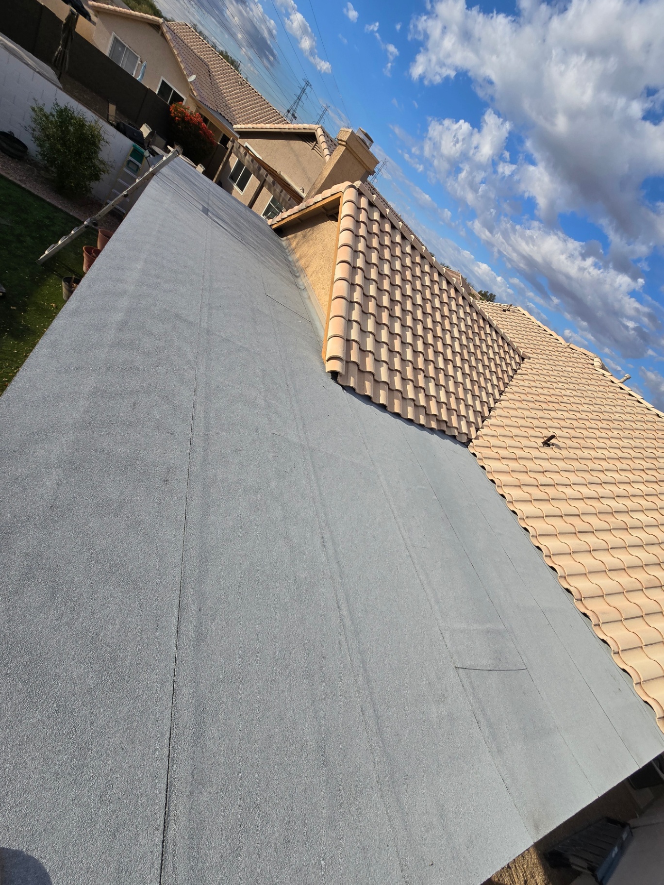 Reflective gray coated patio roof tied into tile roofing on a two-story home