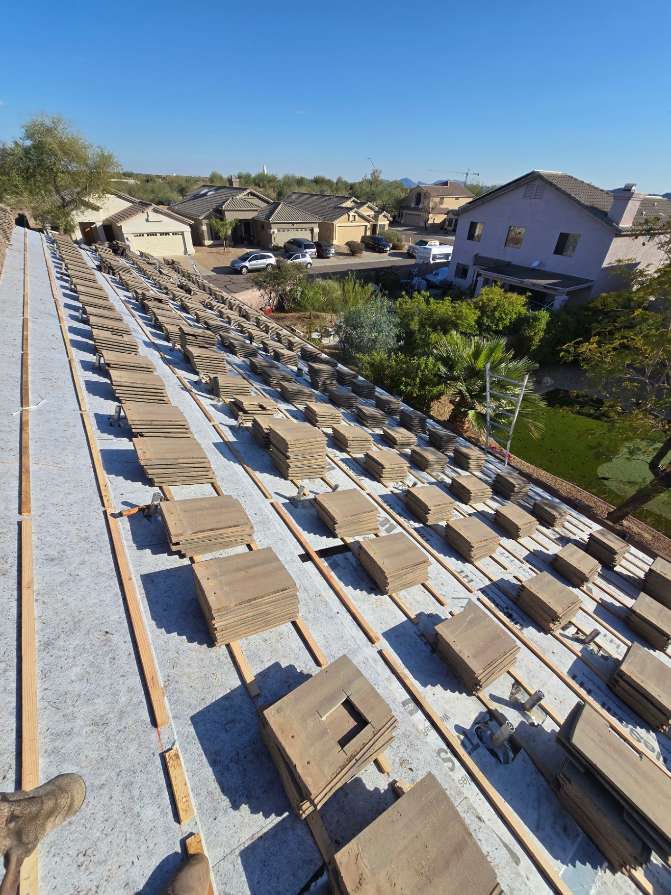 Tile roof load-out with concrete tiles staged across the deck