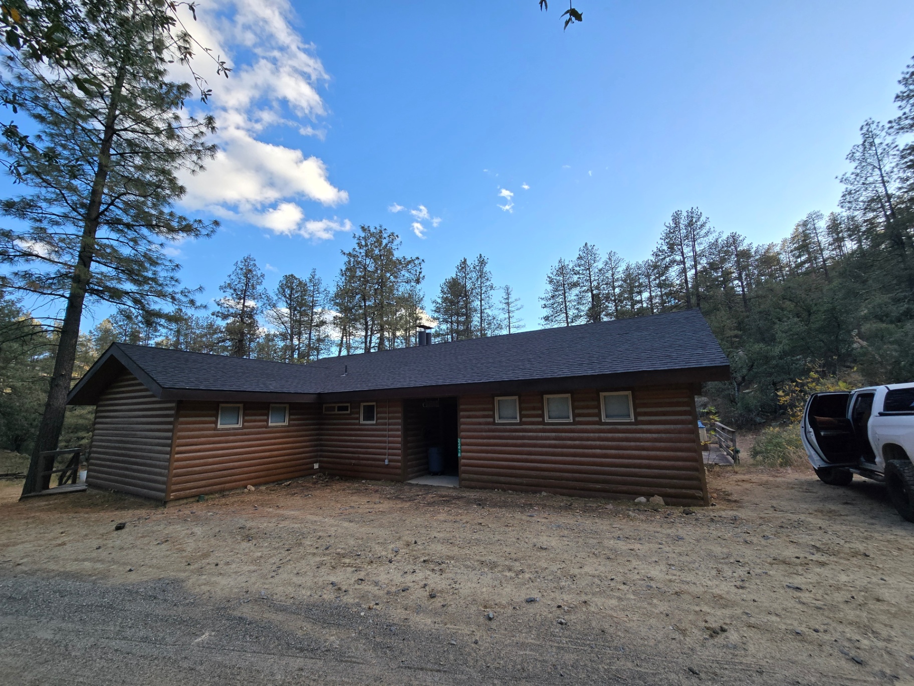 Completed dark architectural shingle roof on a log cabin home in the pines
